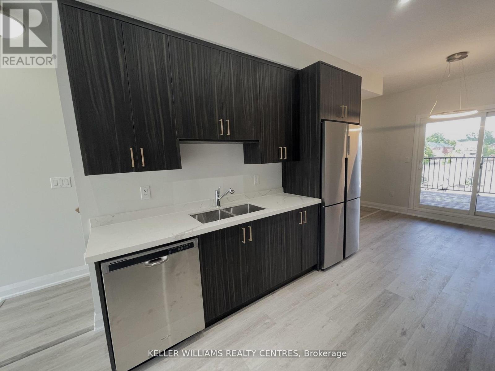 A modern kitchen with dark wood cabinets and stainless steel appliances.