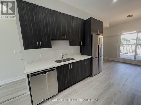 A modern kitchen with dark wood cabinets and stainless steel appliances.