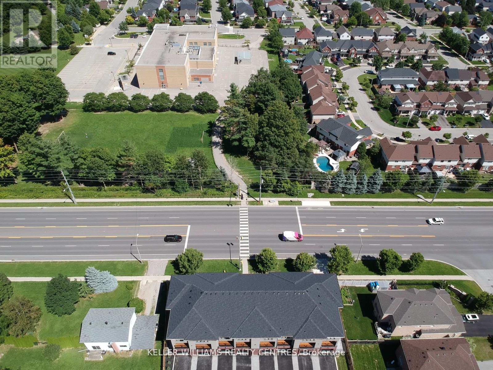 A realtor photo of a suburban area with a road, houses, and a pool.