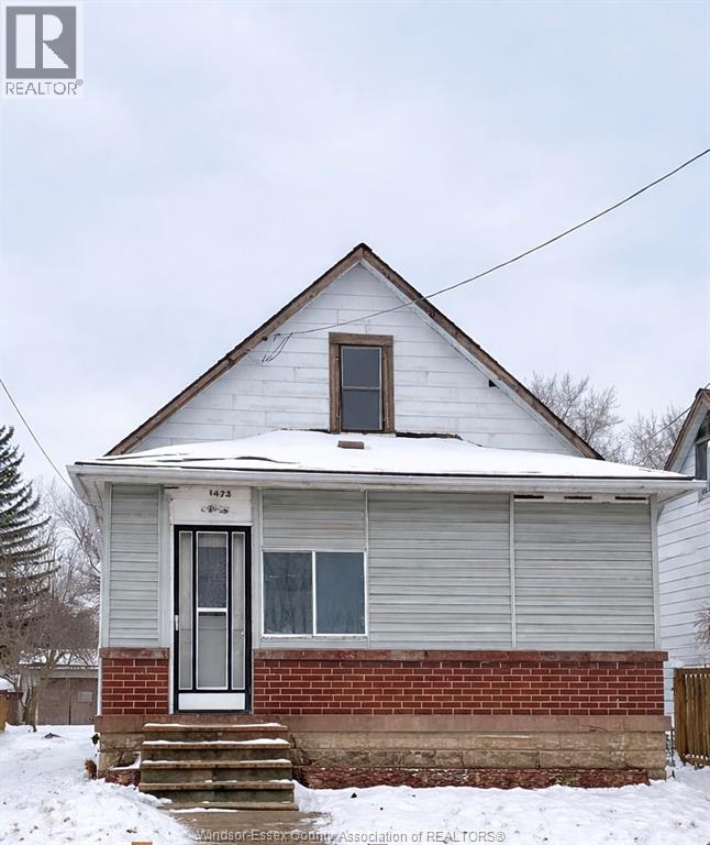 A small house with a snow-covered roof and a brick foundation.