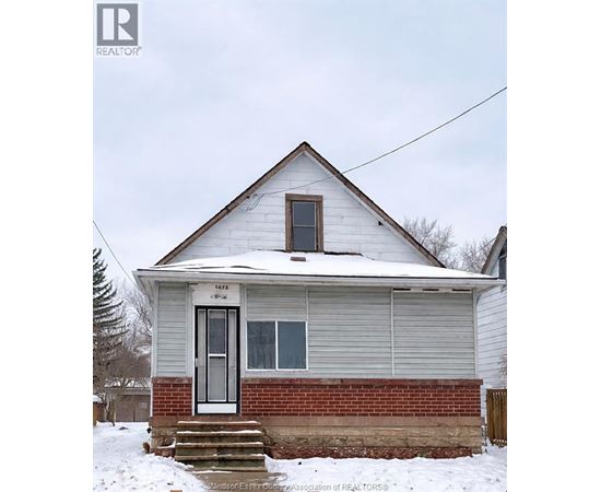 A small house with a snow-covered roof and a brick foundation.