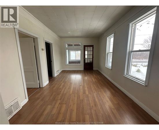 A room with wooden flooring and white walls.