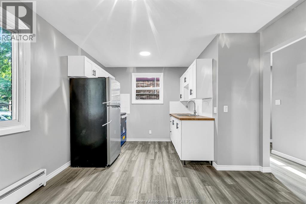 A kitchen with a black refrigerator and white cabinets.
