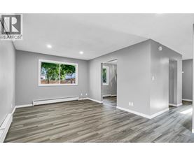 A spacious room with wooden flooring and a large window showing an outdoor view.