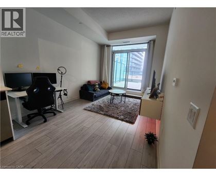 A living room with a black chair and a desk with a computer.