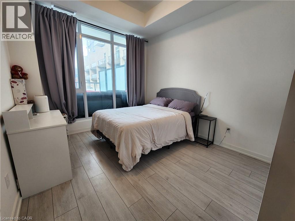 A bedroom with a bed, nightstand, and window with curtains.