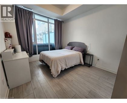 A bedroom with a bed, nightstand, and window with curtains.