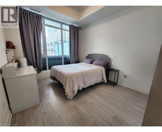 A bedroom with a bed, nightstand, and window with curtains.
