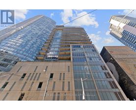 A tall building with a glass facade stands between two other buildings.