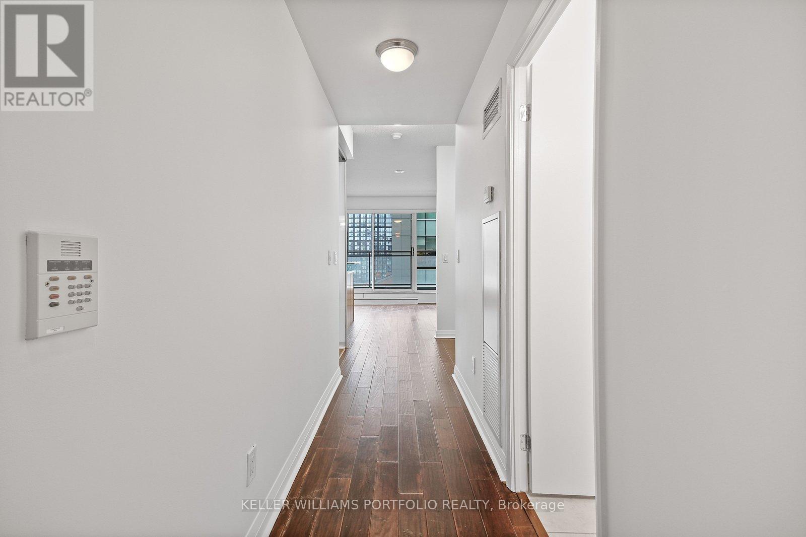 A long hallway with a white wall and a window.