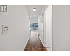 A long hallway with a white wall and a window.