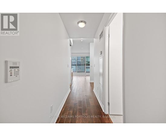 A long hallway with a white wall and a window.