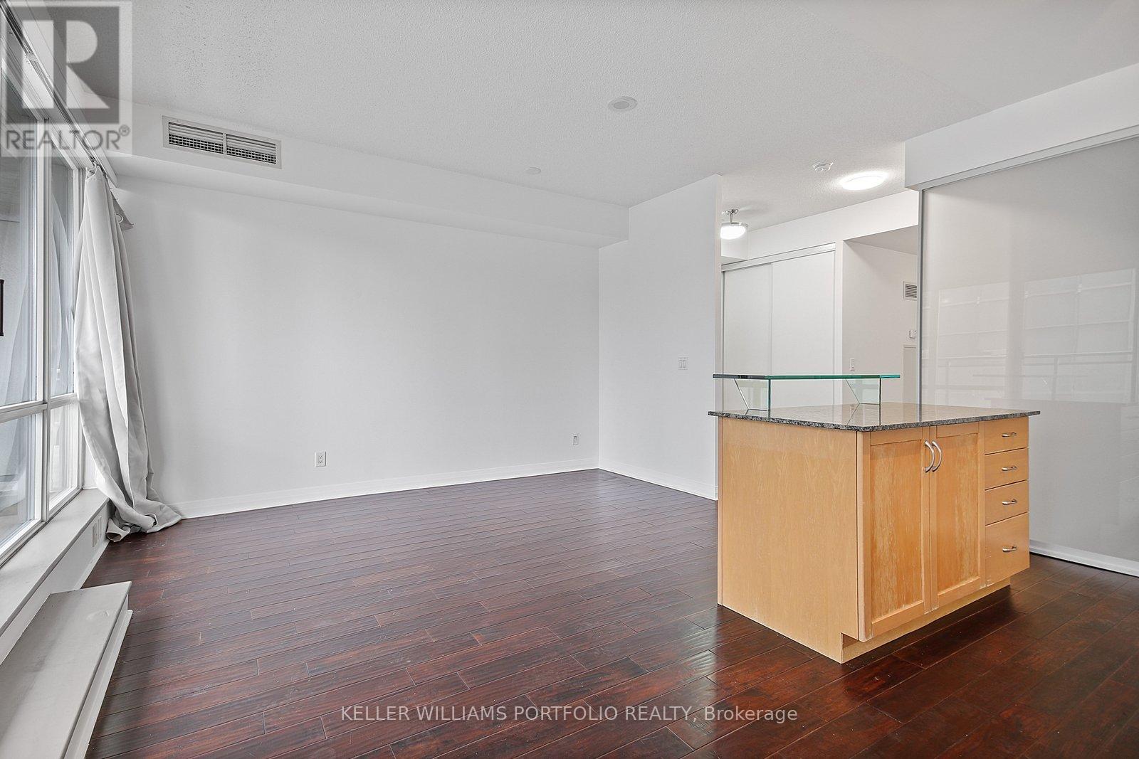 A spacious room with a wooden cabinet and hardwood flooring.