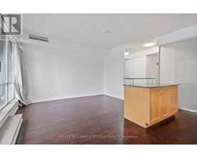 A spacious room with a wooden cabinet and hardwood flooring.