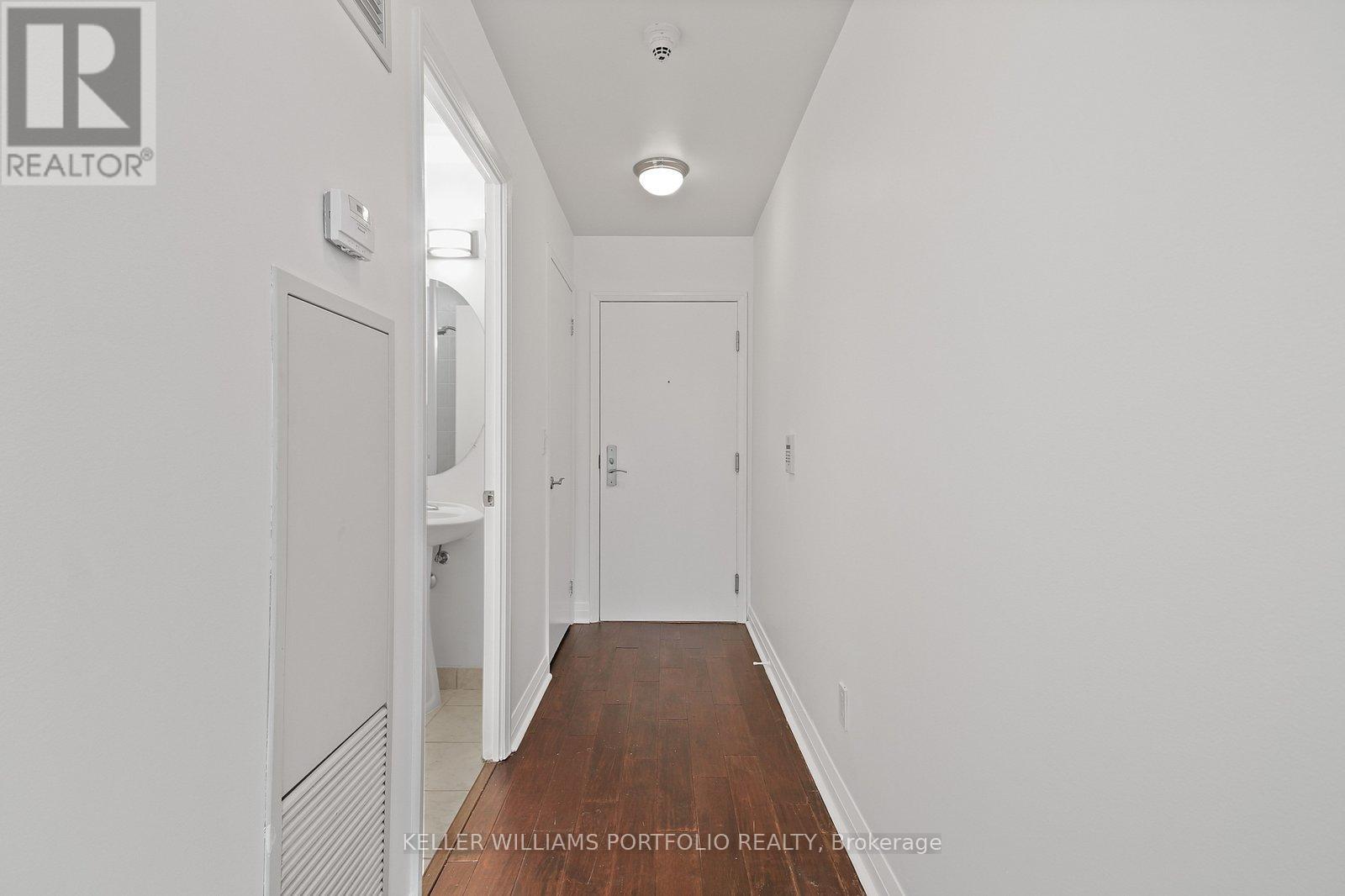 A long hallway with white walls and wood floors.