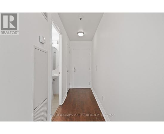 A long hallway with white walls and wood floors.
