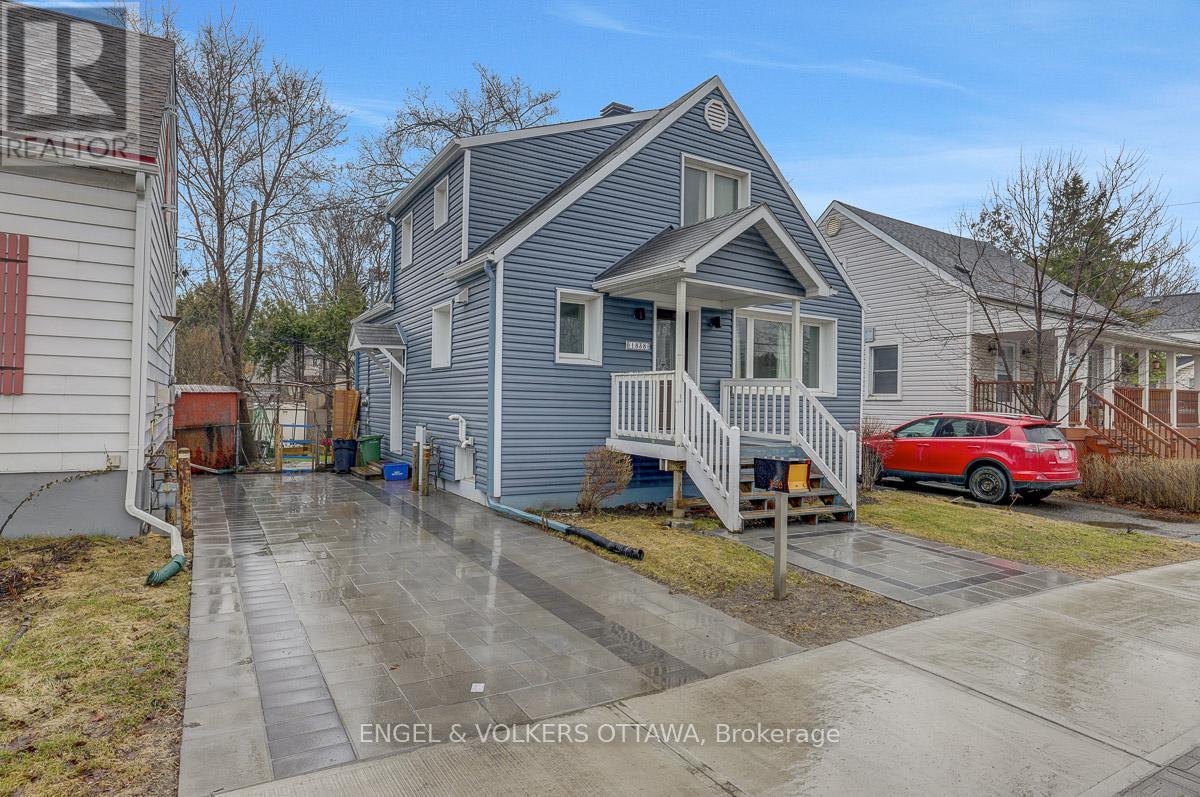 A grey house with a red car parked in front.