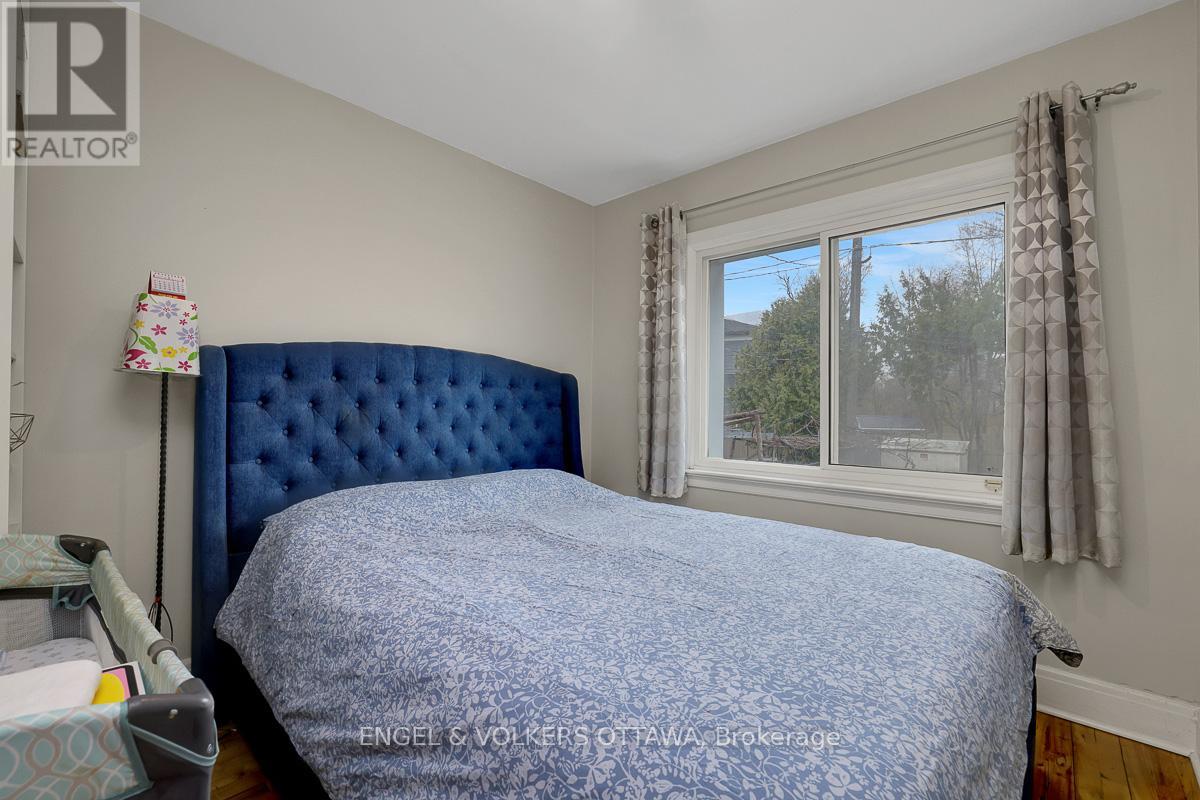A bedroom with a blue bedspread and a window with curtains.