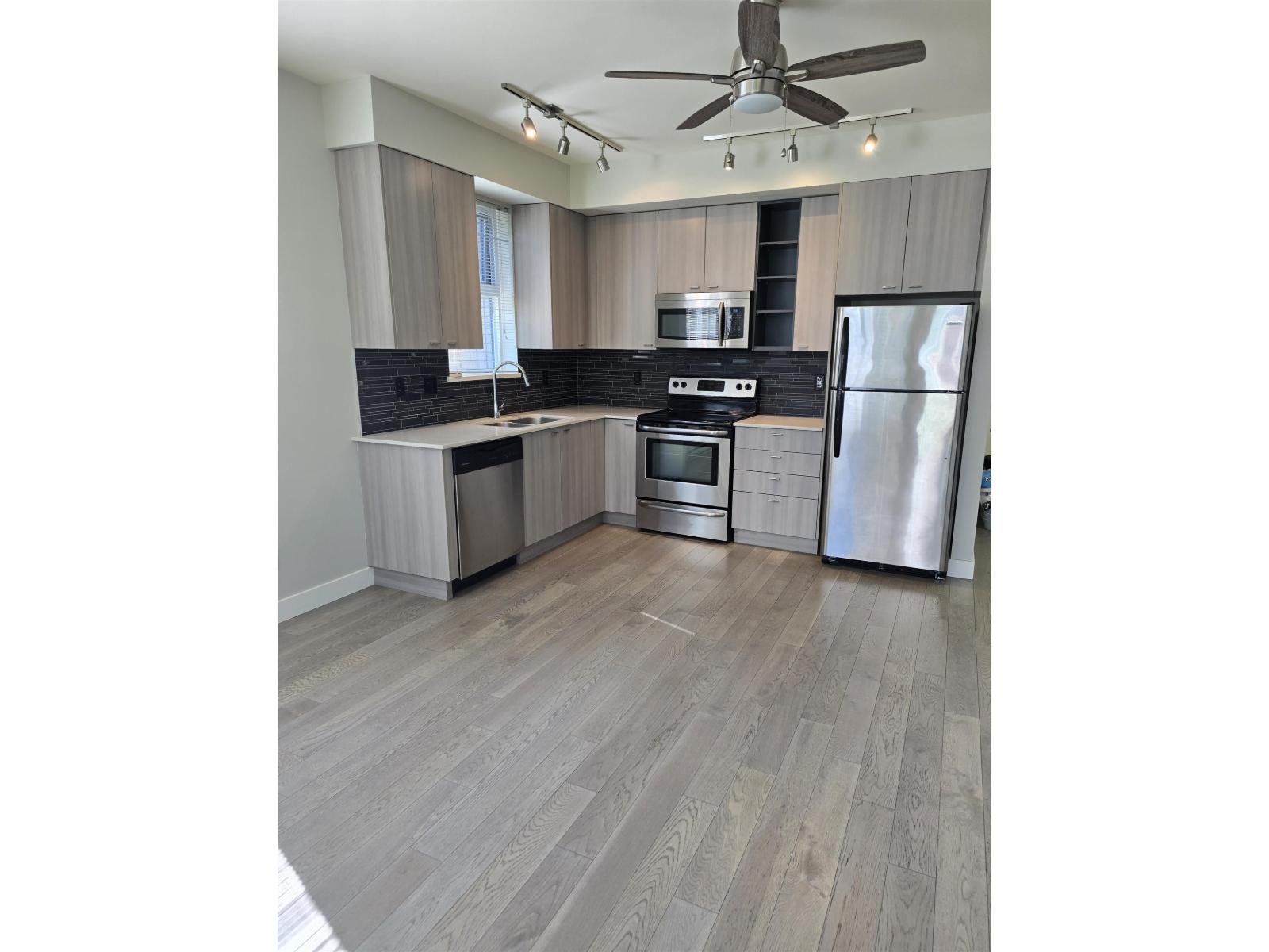 A modern kitchen with a refrigerator, oven, and microwave.