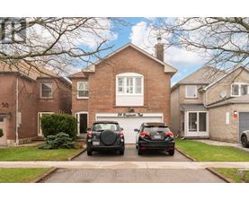 Two cars are parked in front of a brick house.