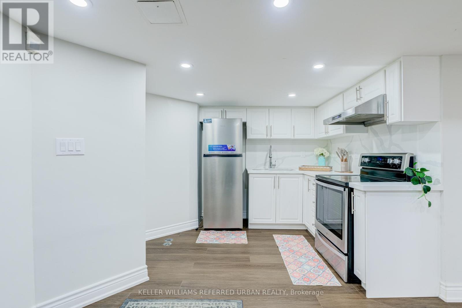 A kitchen with white cabinets and a stainless steel refrigerator.
