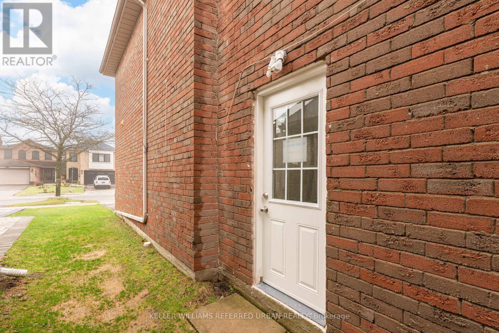 A white door is on a brick wall.