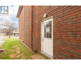 A white door is on a brick wall.