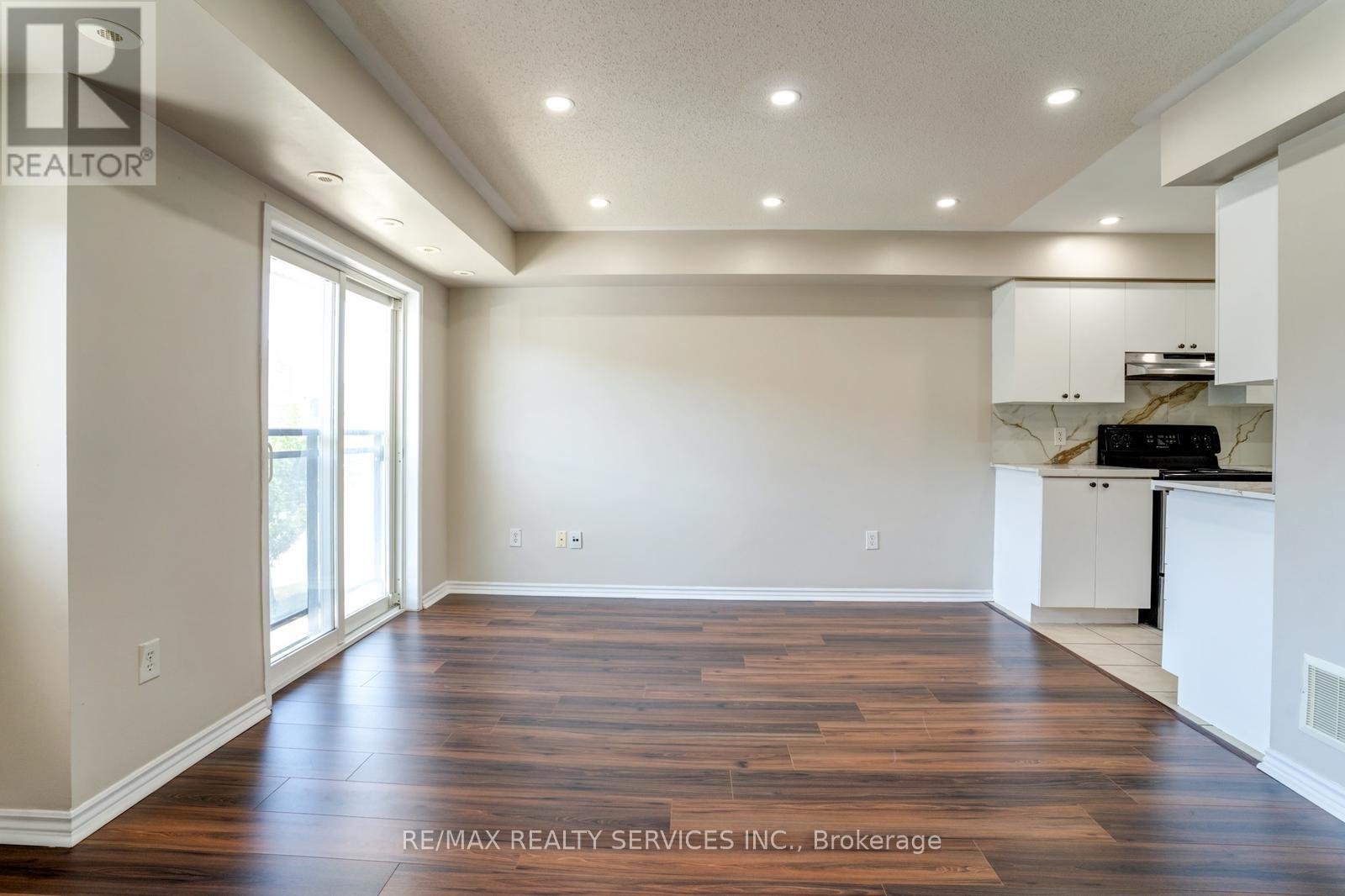 A spacious room with wooden floors and white walls.