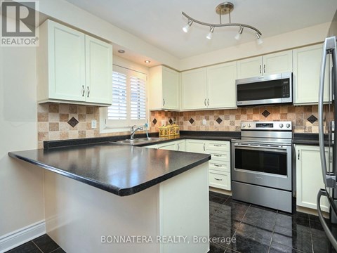 A kitchen with white cabinets and a black countertop.