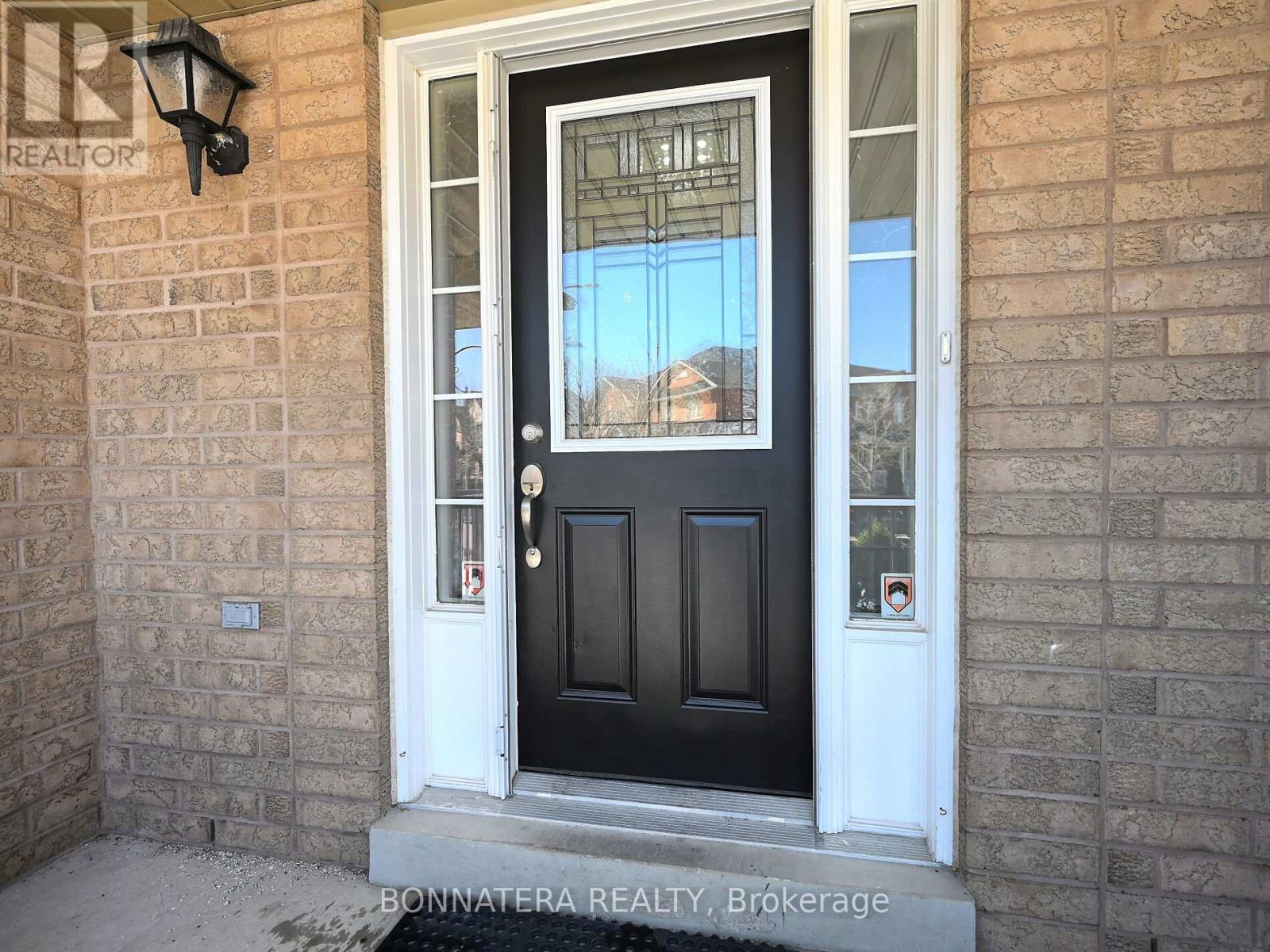 A black door with a glass window is on a brick wall.