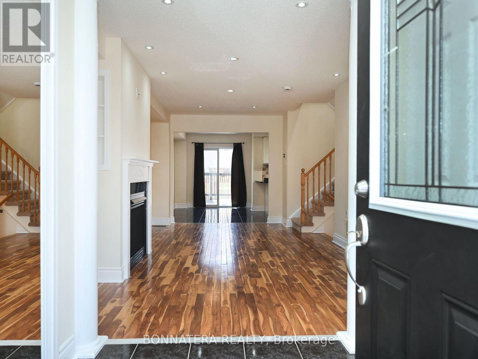 A spacious hallway with wood flooring and white walls.