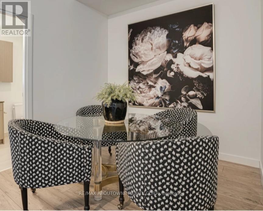 A dining room with a flower picture on the wall and a glass table with a flower vase on it.