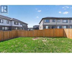 A grassy yard in front of two houses with a wooden fence.
