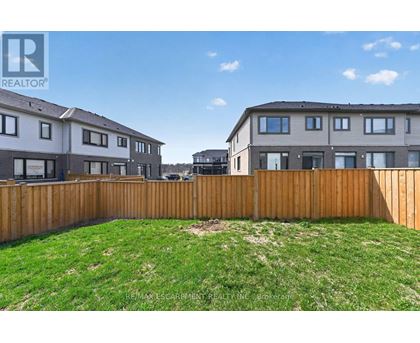 A grassy yard in front of two houses with a wooden fence.