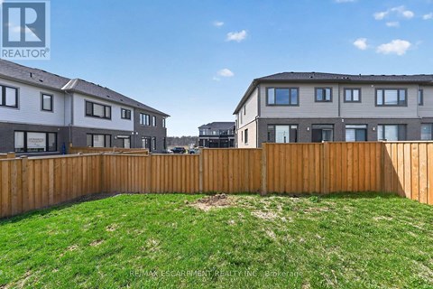 A grassy yard in front of two houses with a wooden fence.