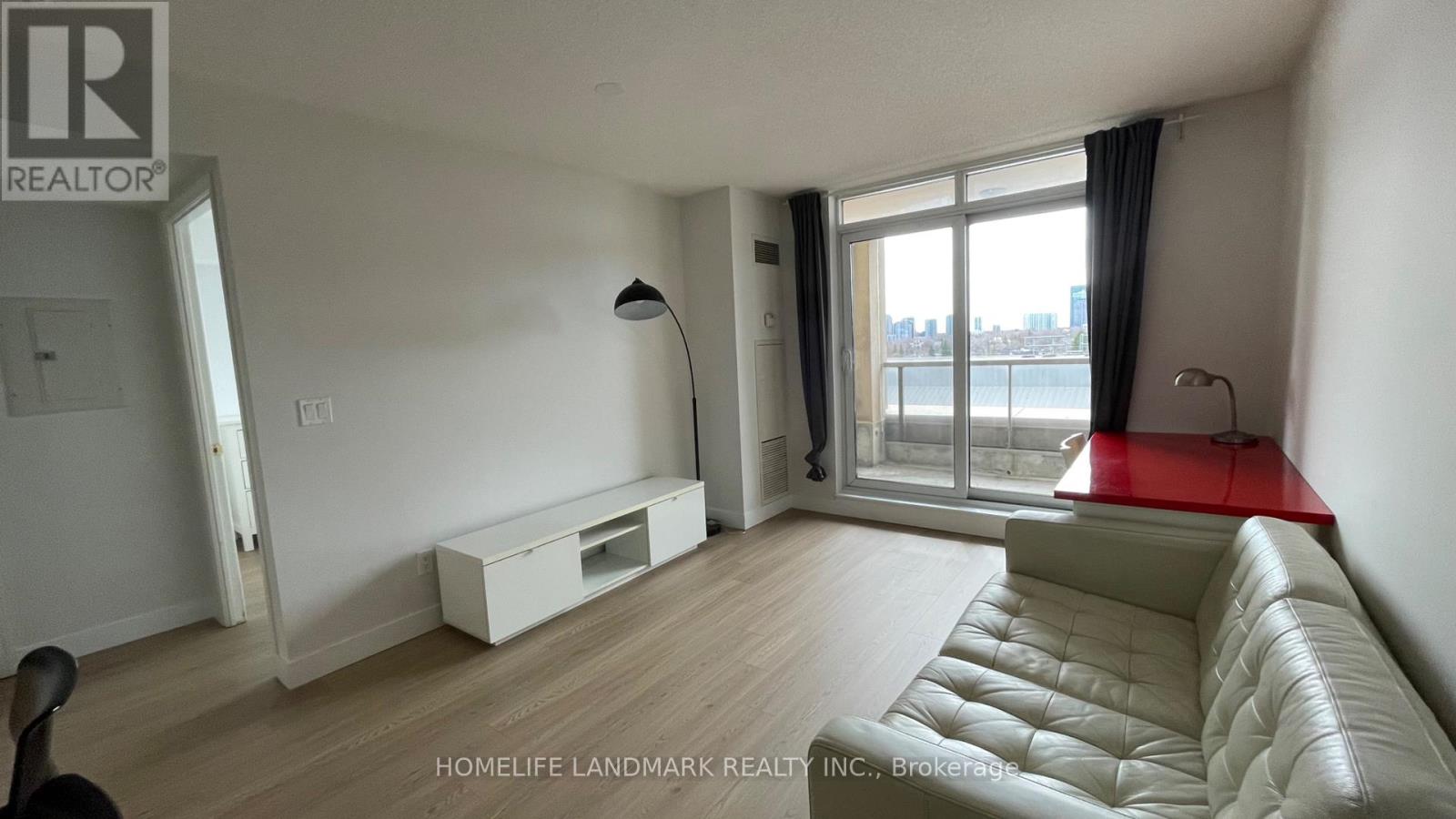 A living room with a white couch and a red table.