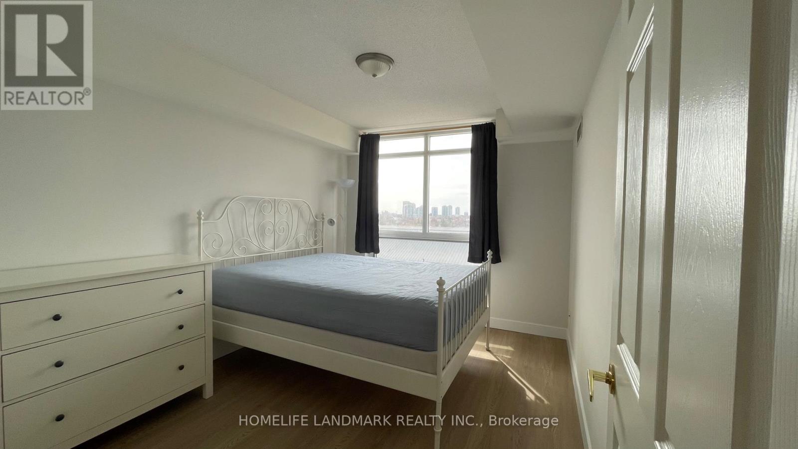 A bedroom with a bed, dresser, and window.
