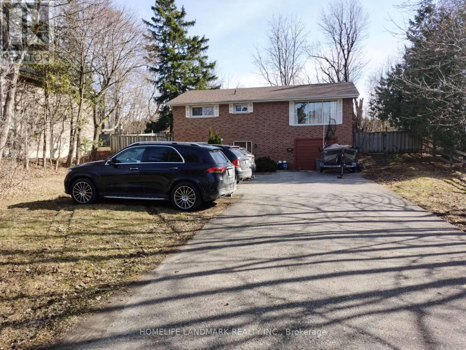 A black car is parked on a driveway in front of a house.