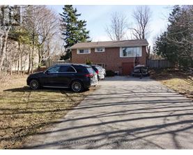 A black car is parked on a driveway in front of a house.