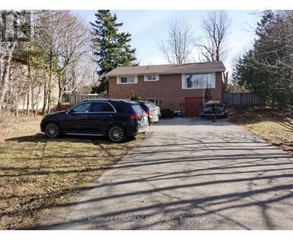 A black car is parked on a driveway in front of a house.