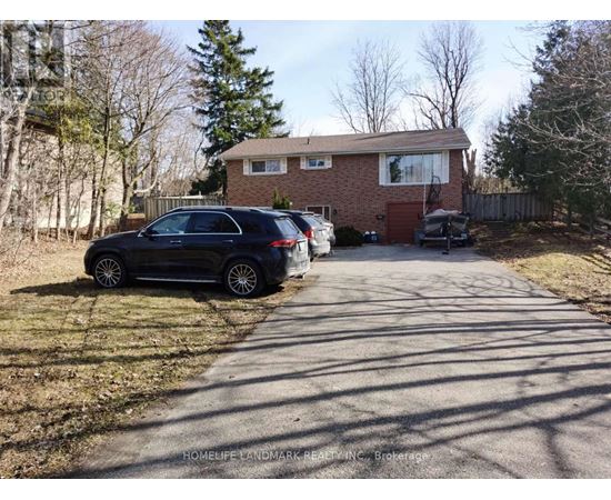 A black car is parked on a driveway in front of a house.