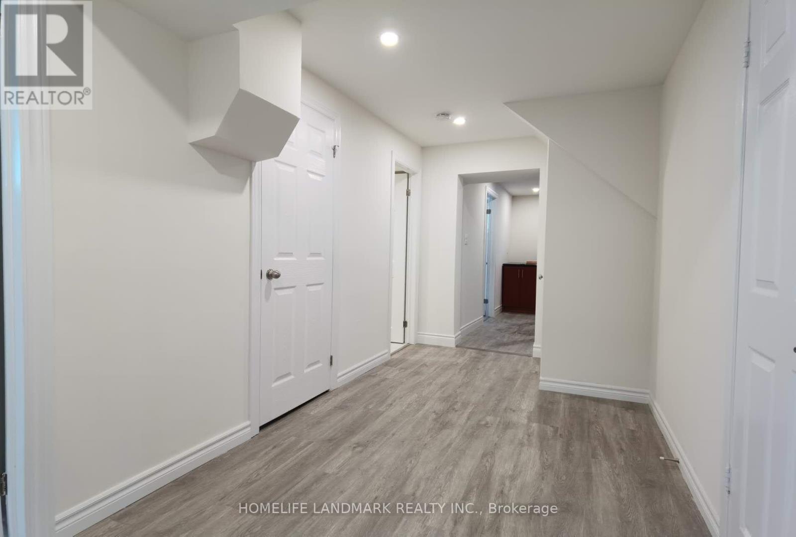 A hallway with white walls and wood flooring.
