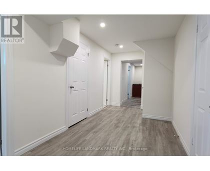 A hallway with white walls and wood flooring.