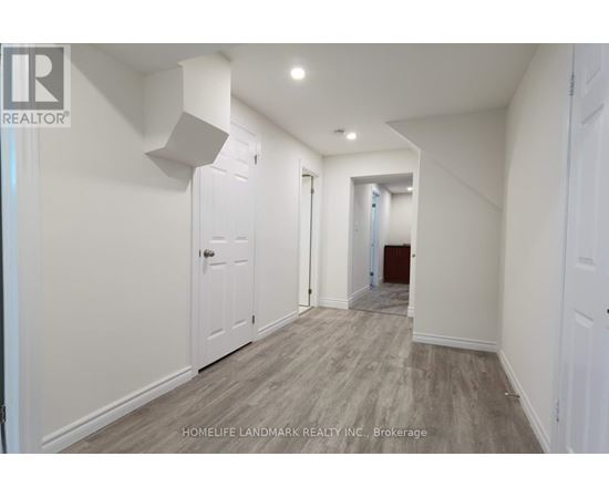 A hallway with white walls and wood flooring.
