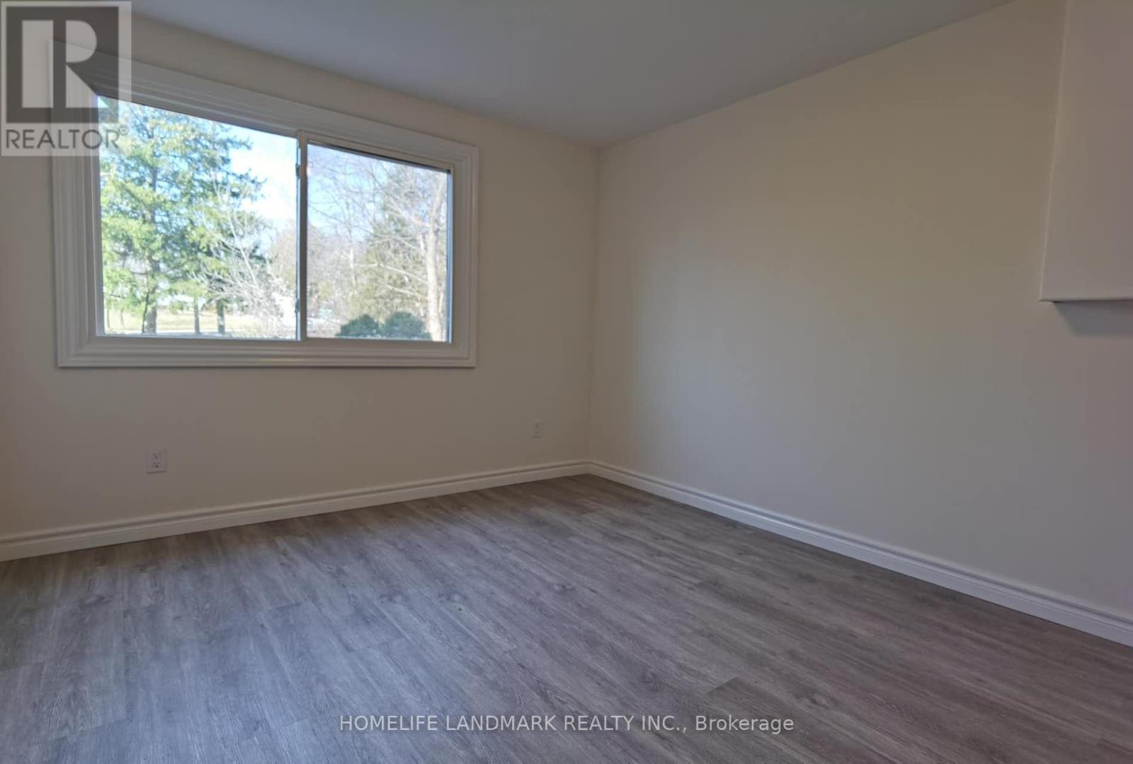 A room with a window and a wooden floor.