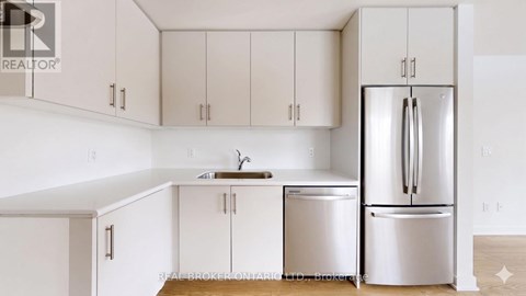 A kitchen with white cabinets and a white fridge.