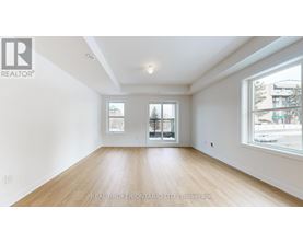 A spacious room with wooden flooring and two windows.