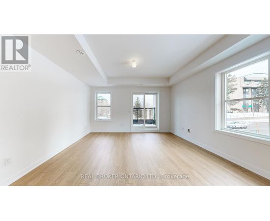 A spacious room with wooden flooring and two windows.