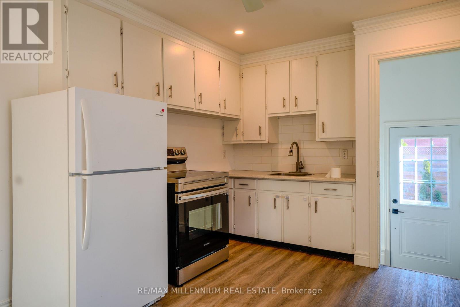 A kitchen with white cabinets and a white refrigerator.