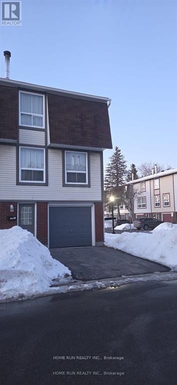 A two-story house with a garage and a driveway covered in snow.